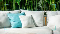 Garden couch with white cushions and one turquoise scatter cushion to support a cleaning guide on how to clean outdoor cushions