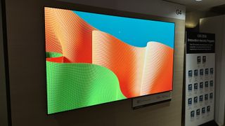 Wall-mounted LG G4 OLED TV demoing a blue, green and orange graphic