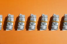 Pattern of wrapped american one hundred dollar bills on orange background.