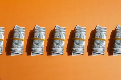 Pattern of wrapped american one hundred dollar bills on orange background.