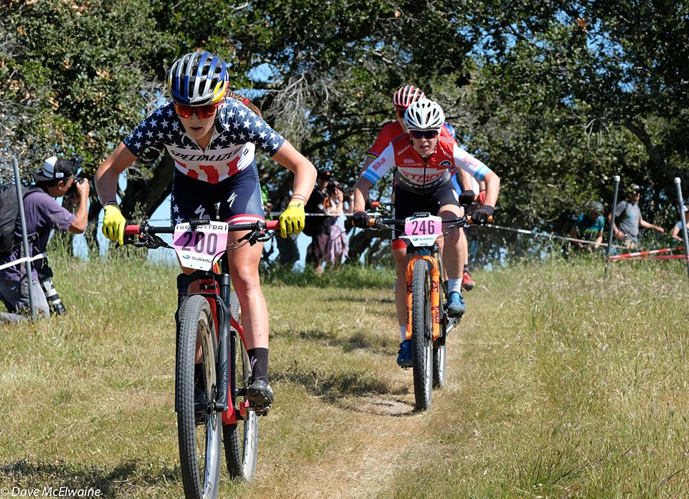Kate Courtney (Specialized) leading Chloe Woodruff through some trees at the top of the course