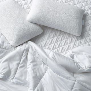 Pillows and a comforter on top of the Sijo TempTune Mattress Pad.