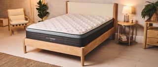 Image shows the Helix Sunset Luxe mattress on a light wooden bed frame in a neutral coloured bedroom