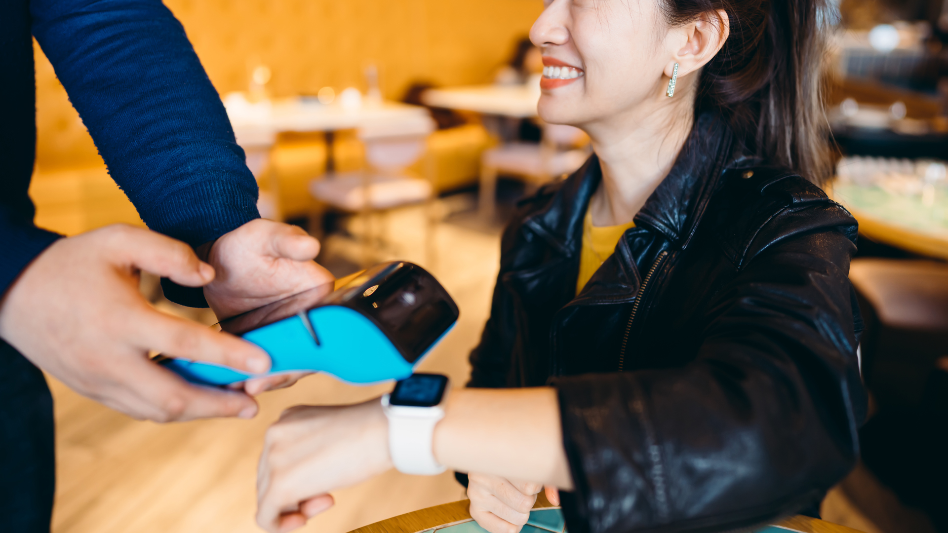 woman using an apple watch to make a payment on a pos terminal