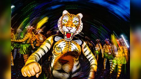 'Tiger dancer' performing Pulikali during India's Onam festival, with spiral of lights behind