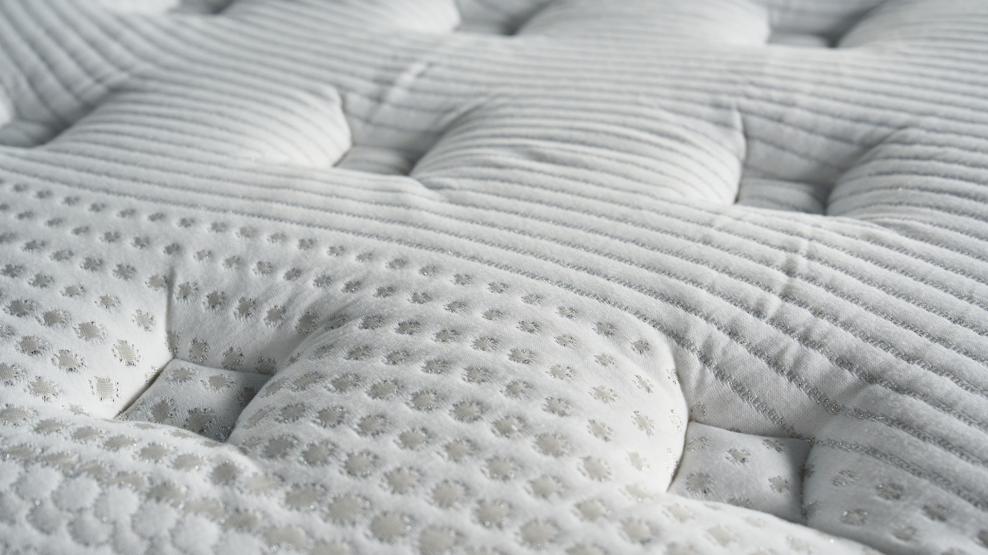 A close-up shot of the plush white surface of the Bear Elite Hybrid mattress with silver stitched detailing