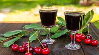 Glasses of tart cherry juice sitting together with whole cherries