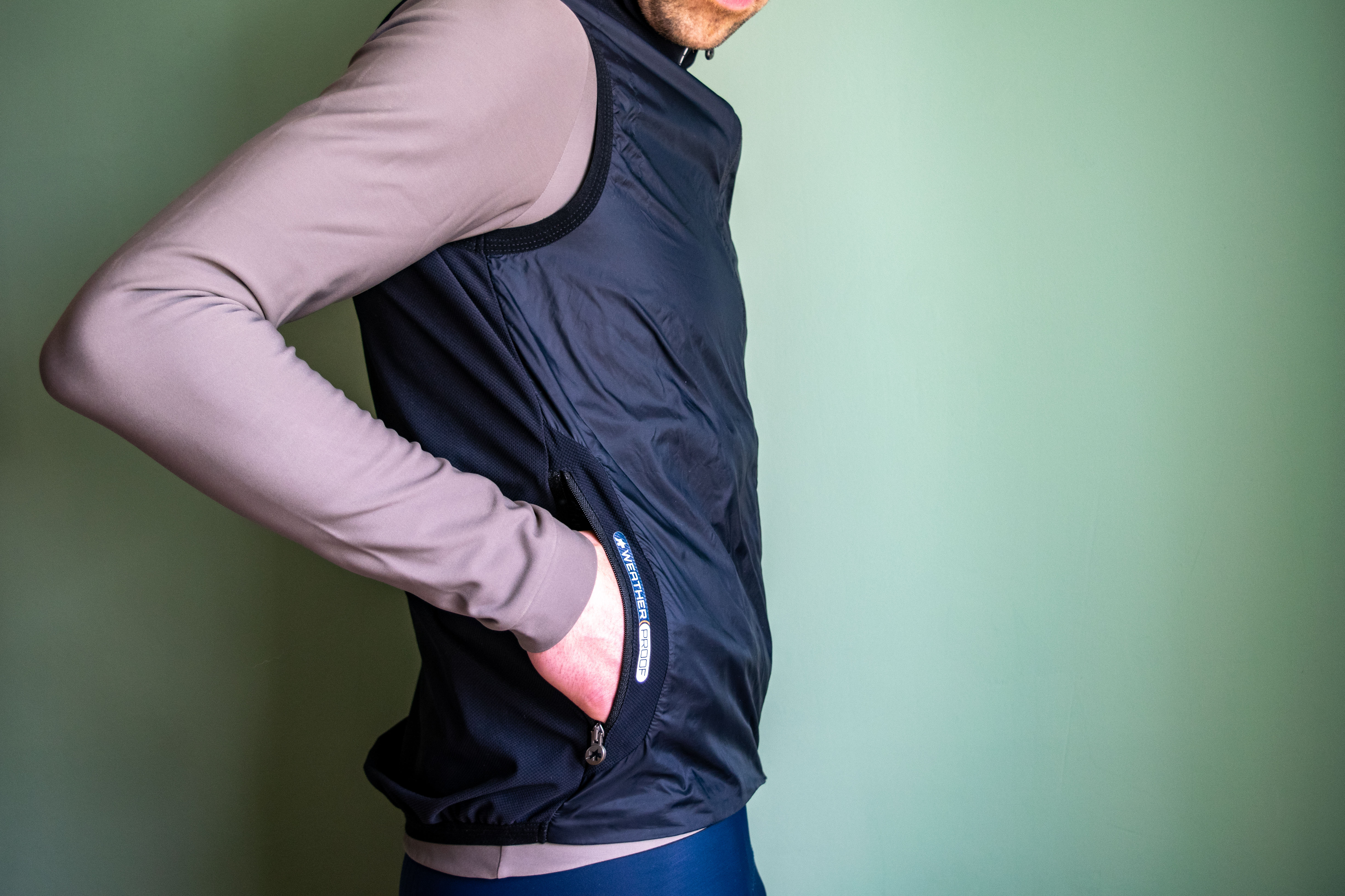 A man wearing a black Assos Tactica gilet over a grey long sleeve shirt