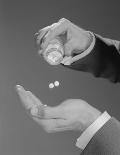 A man shakes pills out into his hand