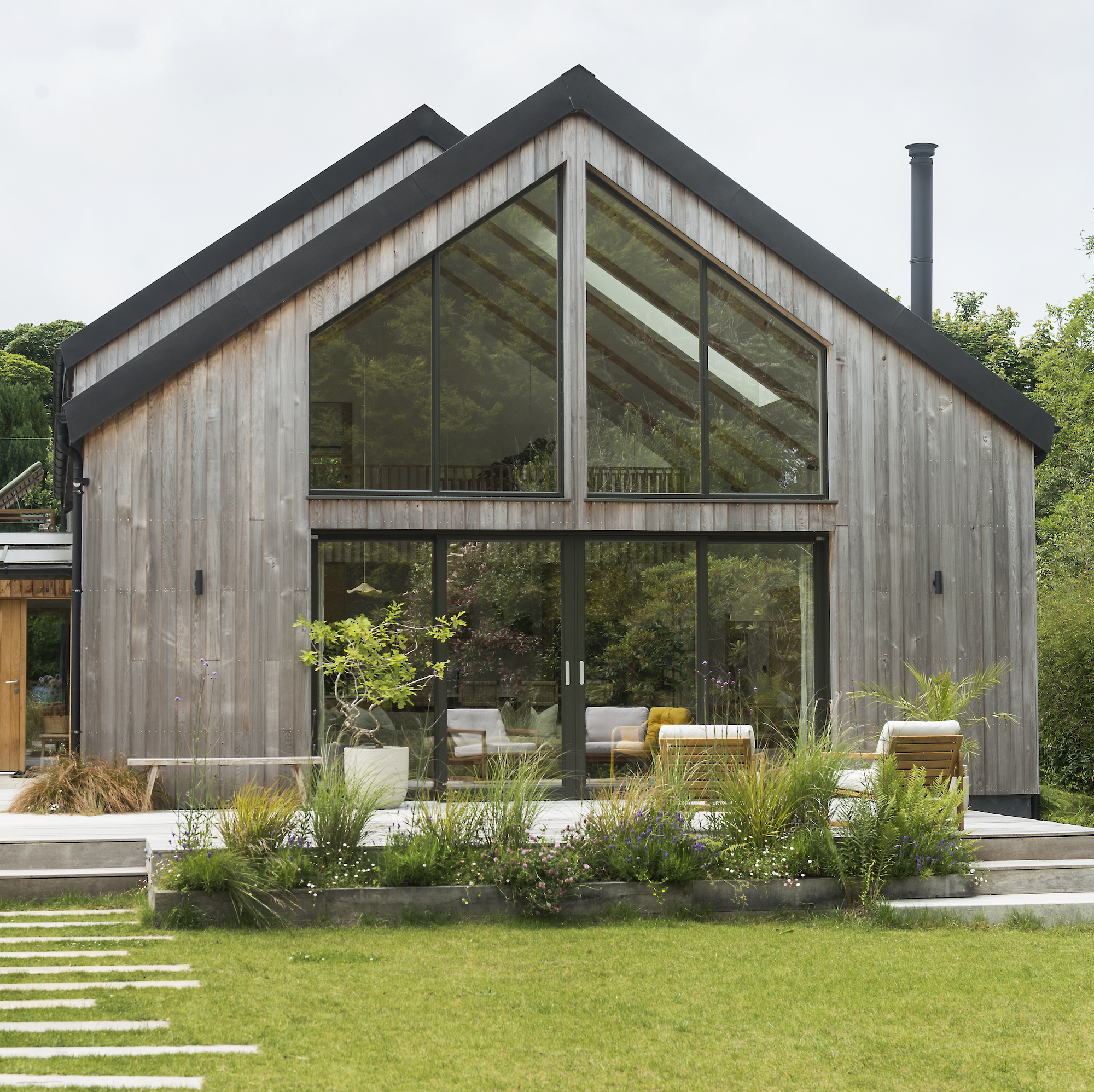 exterior of contemporary house with cedar cladding and pitched roof with large glazed windows overlooking garden