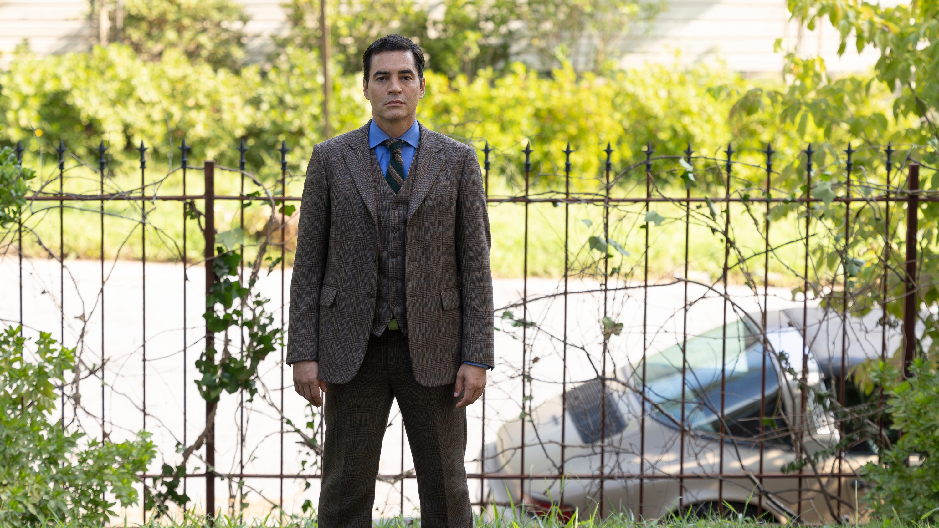 RAMÓN RODRIGUEZ as Will Trent standing in front of a wire fence and looking at the camera.