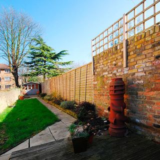 narrow lawn area with bricked wall