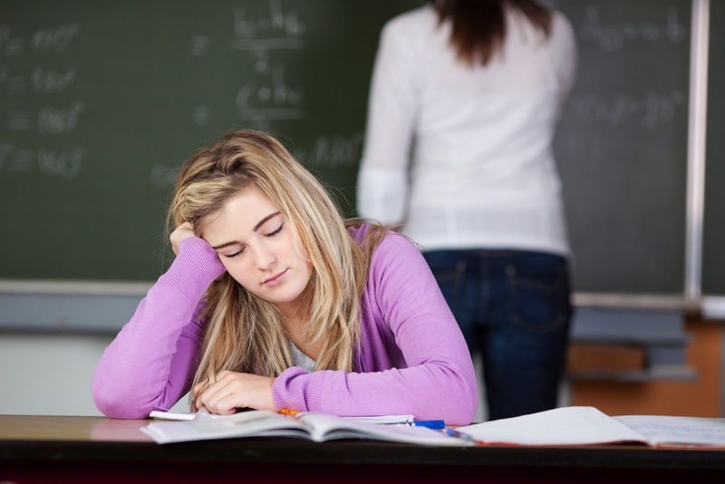 A teen girl dozes off in a classroom.