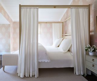 four poster bed with drapes in room with pink wallpaper