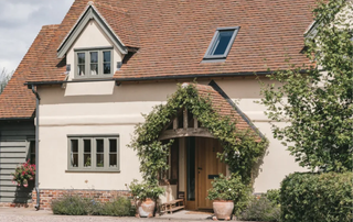 oak frame porch on cream rendered cottage with tiled roof, planting around front of oak frame