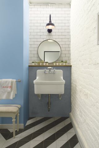 blue bathroom with basin in alcove, metro tiles, mirror, wall light, black and white floor tiles