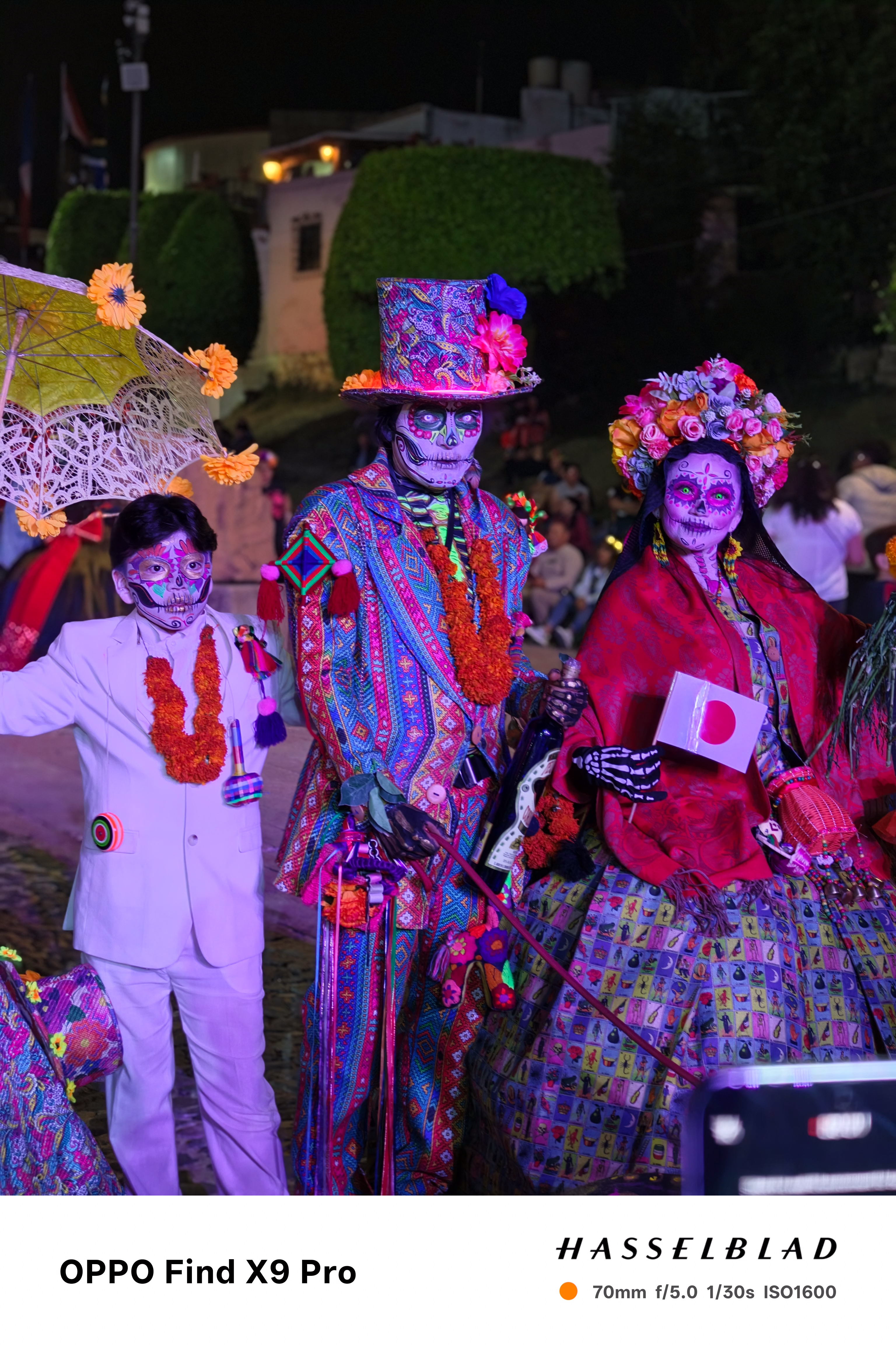 Three people at night wearing luminescent day of the dead outfits