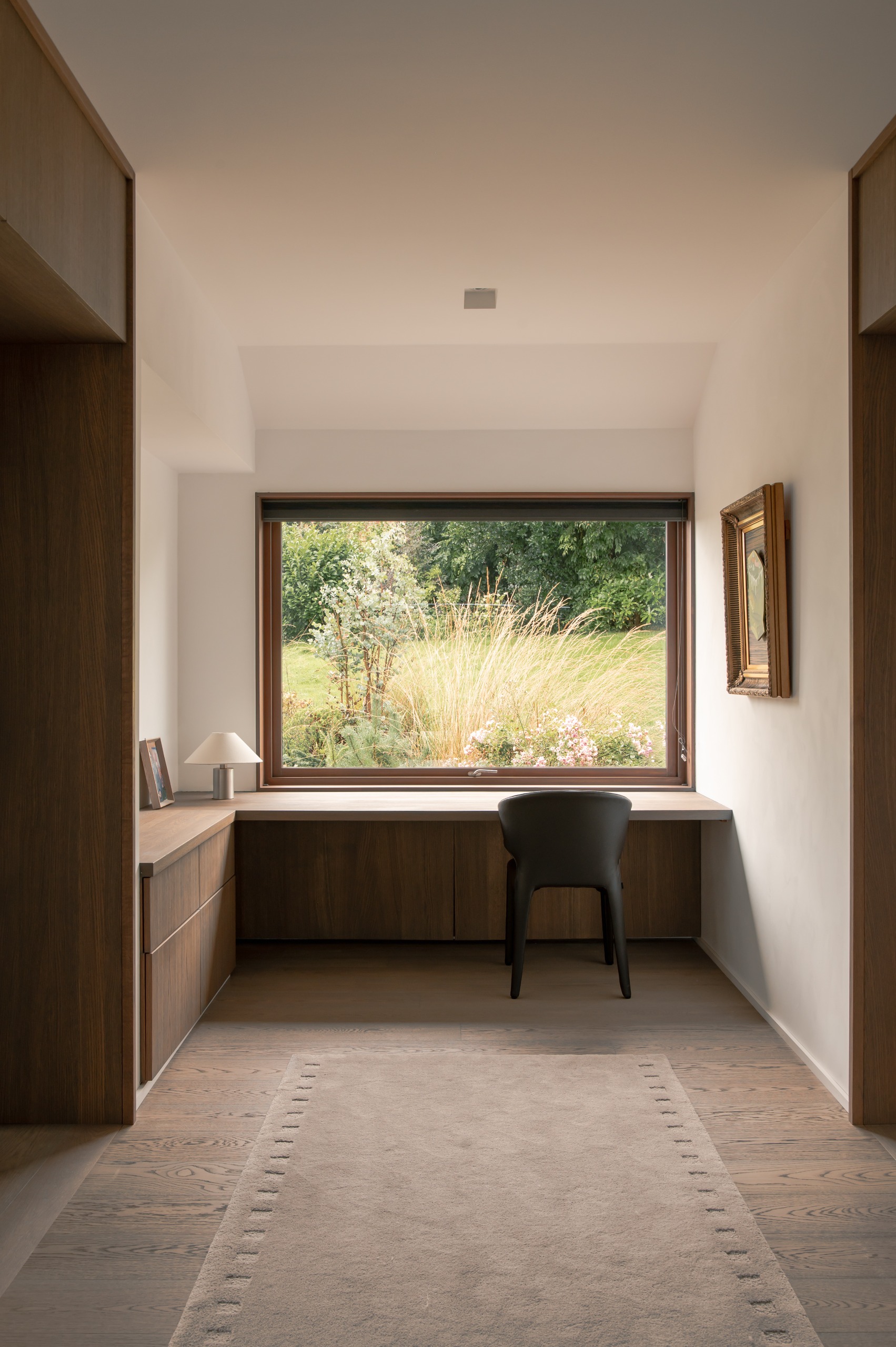 a wood-panelled alcove with a grey sofa inside and a soft, warm wall light inside the alcove