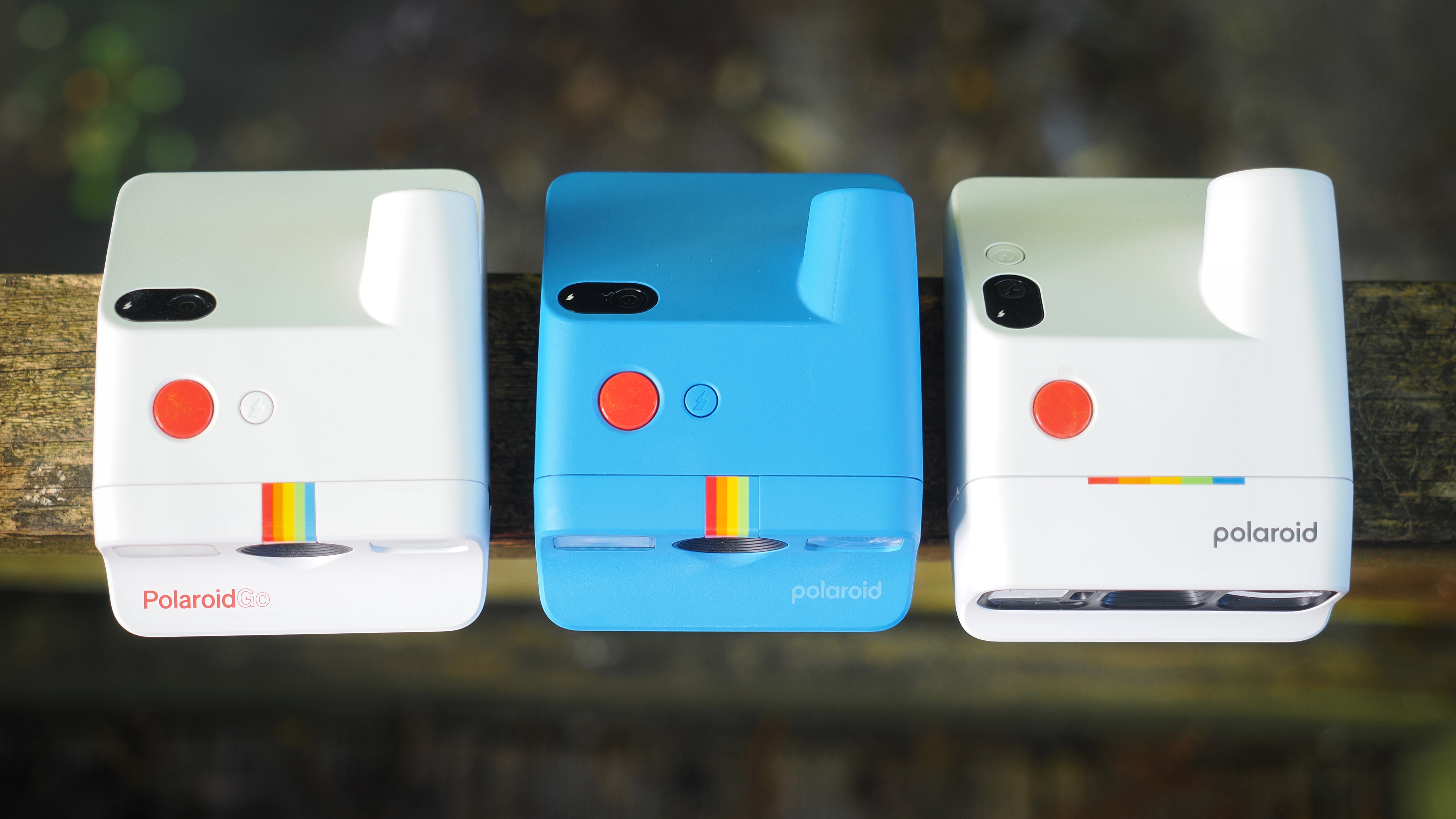 Top-down view of the Polaroid Go, Gen 2 and Gen 3 sitting on a wooden surface outdoors.