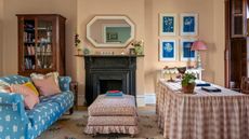 a pink womens home office with an original black fireplace, pink gingham skirted desk, floral ottoman and blue floral sofa