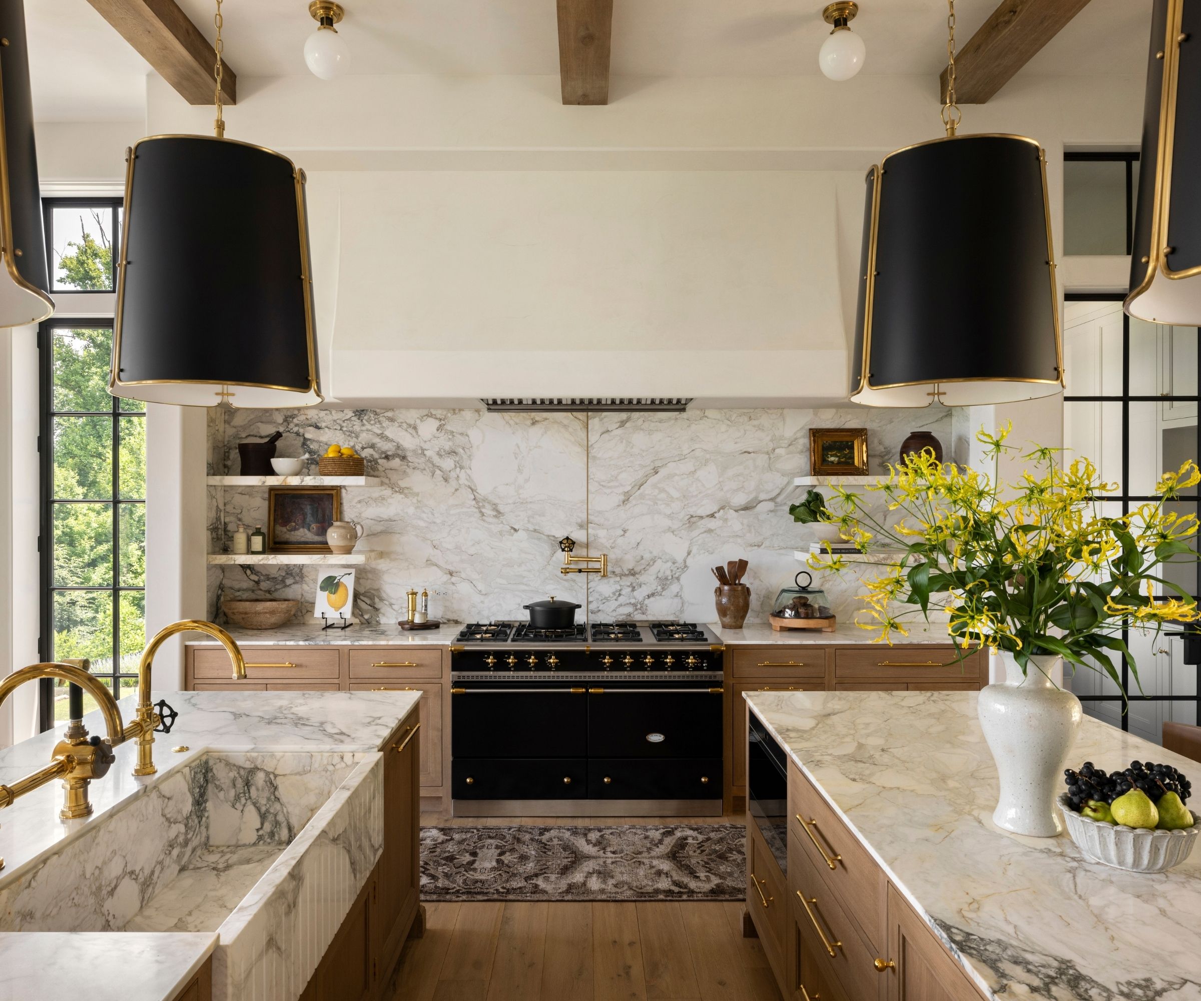 A warm neutral kitchen with wooden cabinets, marble backsplash, and oversized pendants