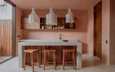 A kitchen with salmon pink walls and a beige lighting piece