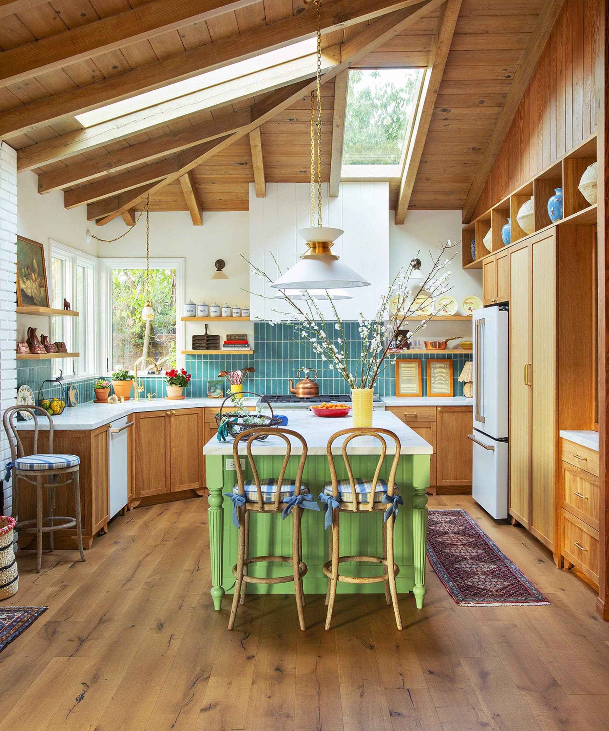A wooden kitchen with vaulted ceilings, blue backsplash tiles, and a bright green island