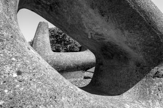 A black & white photo of a concrete sculpture. It's asymmetrical, with rounded edges and hollow.