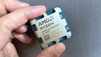 A photo of an AMD Ryzen 9 9950X3D2 Dual Edition processor held between a person's finger and thumb