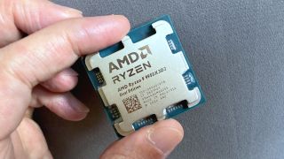 A photo of an AMD Ryzen 9 9950X3D2 Dual Edition processor held between a person's finger and thumb