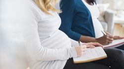 Two pregnant people sitting and writing