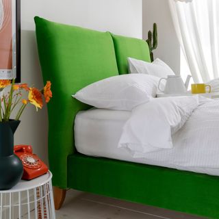 A bright green headboard in a neutral bedroom