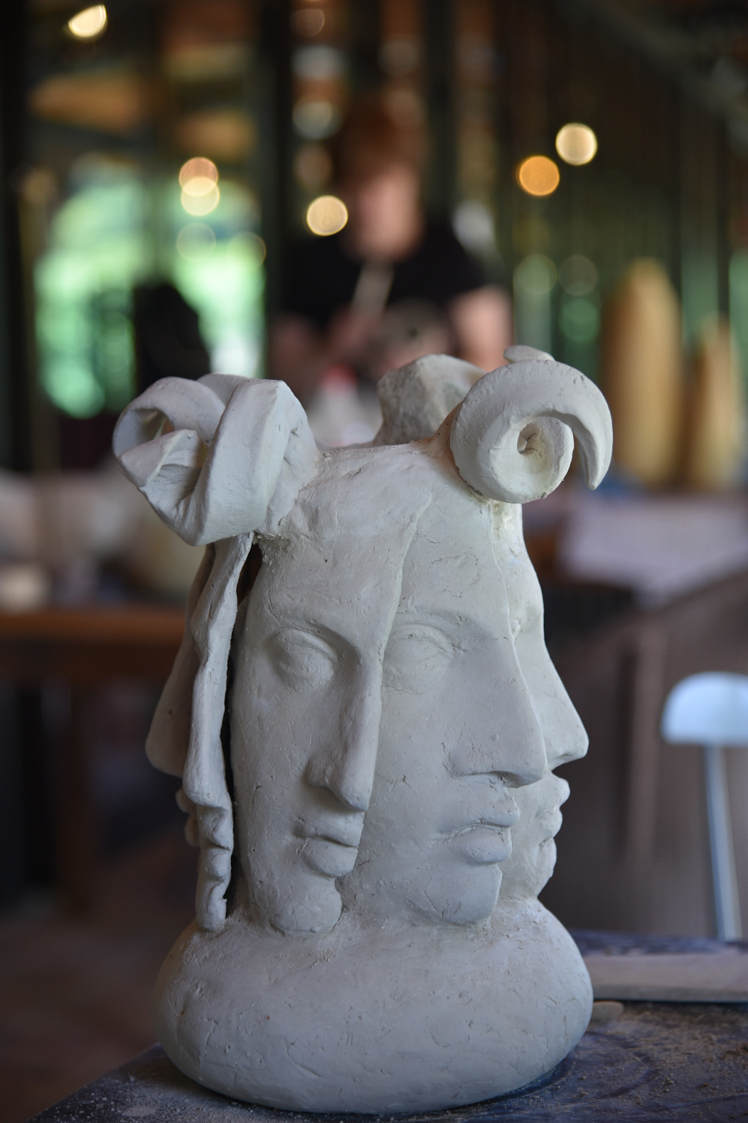 A multi-face ceramic sculpture with curly hair and thick lips.