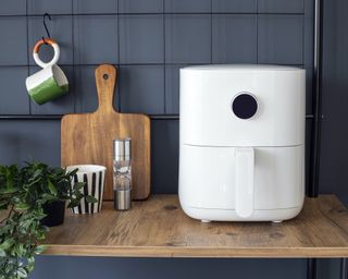 A white air fryer on a wooden countertop in a blue kitchen