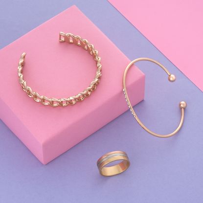 Gold bangles and ring on a pink and purple background