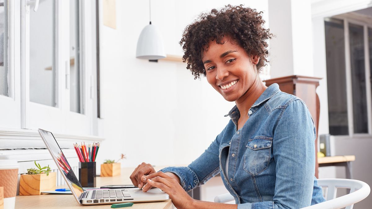 Woman smiling at laptop with pencils next to her