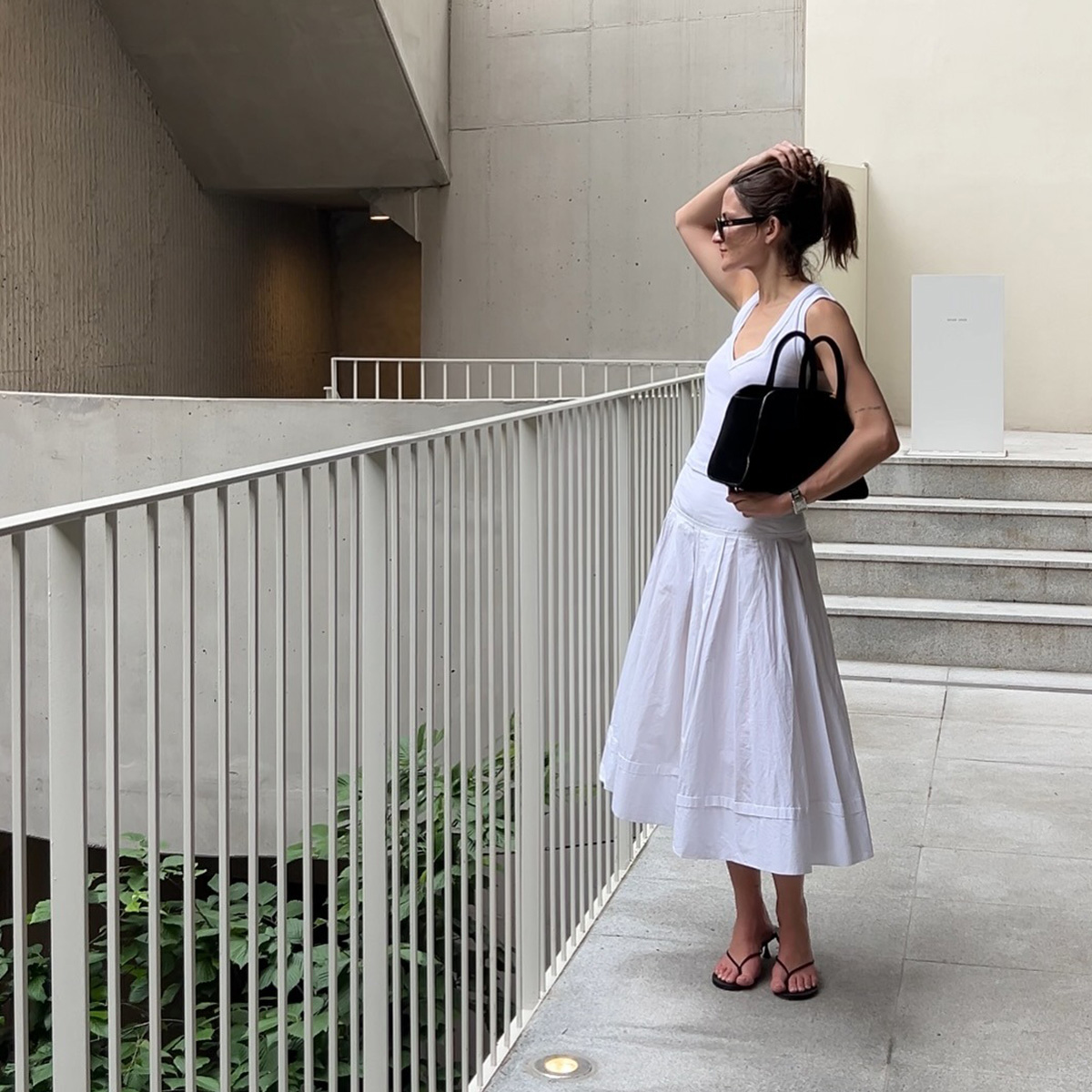 Eliza Huber in Seoul, South Korea wearing a white Zara tank top, white poplin skirt by Lafayette 148, a black COS bag, and black Studio Amelia sandals.