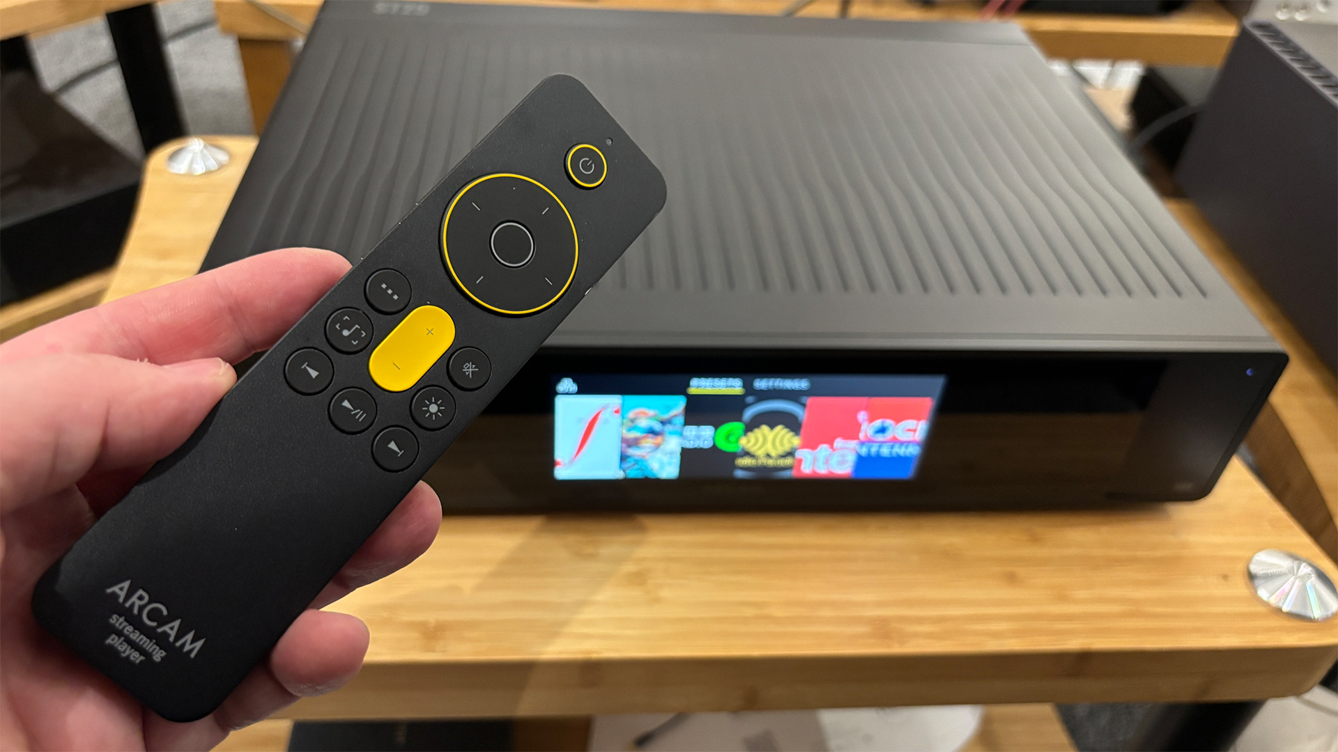 Arcam ST25 music streamer remote control held in hand above streamer
