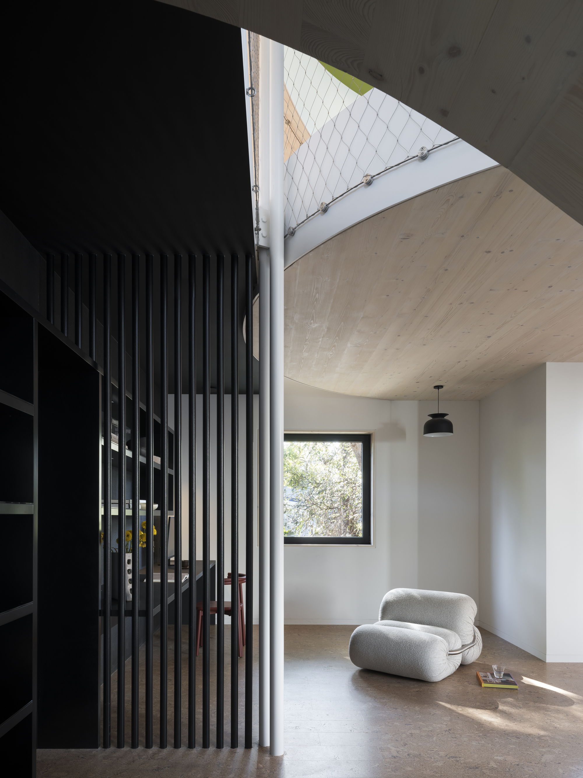 room with cork flooring, white armchair, timber ceiling, and black slatted timber feature wall
