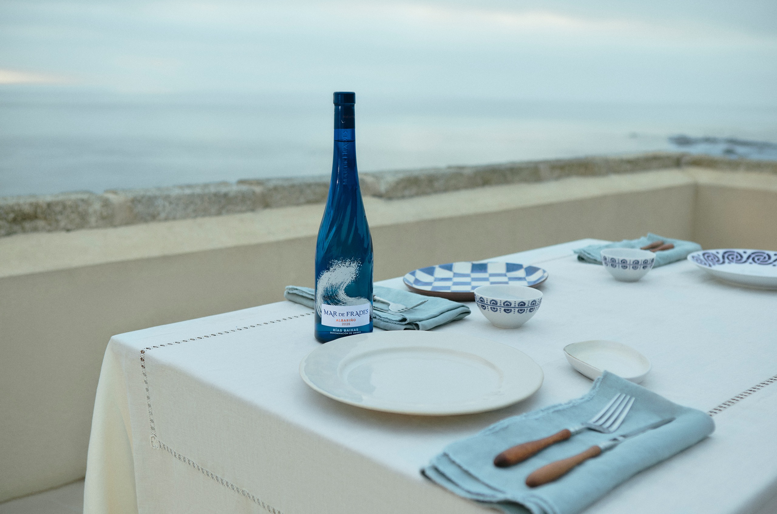 Blue bottle of white wine on a table in front of the sea