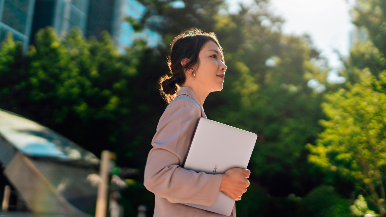 Dell laptop being carried by a person outside near some trees