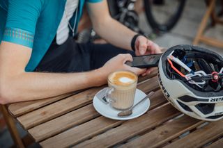 Image shows rider looking at social media on a phone at a cafe stop.