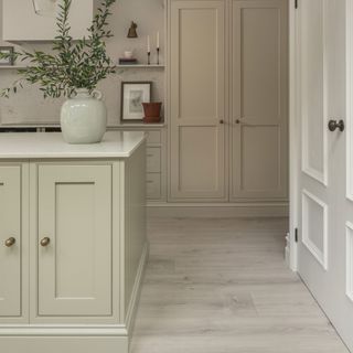 off white kitchen with white laminate flooring, vase, marble splash back