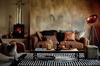 Blaboa three seater leather sofa from DFS in a moody living room with plaster effect wall, a wood burning stove and a striped rug