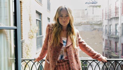 Olivia Wilde on a balcony wearing a pink textured Chanel suit with wide leg pants and an oversize blazer