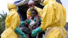 A woman suspected of suffering from Ebola is helped into a van by aid workers.