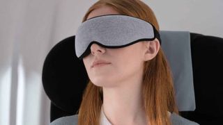Woman wearing Ostrichpillow eye mask on a flight