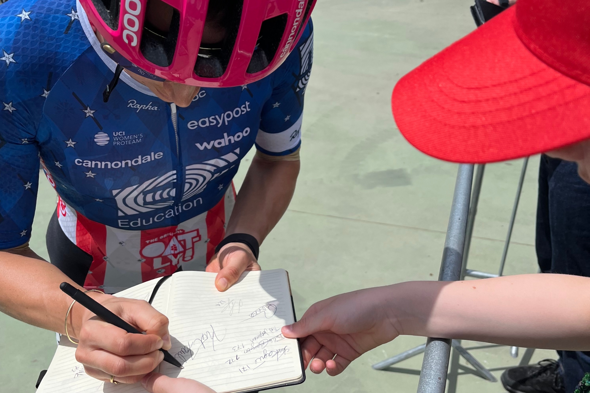 Olympic women's road race champion, Kristen Faulkner, signs a girls autograph book