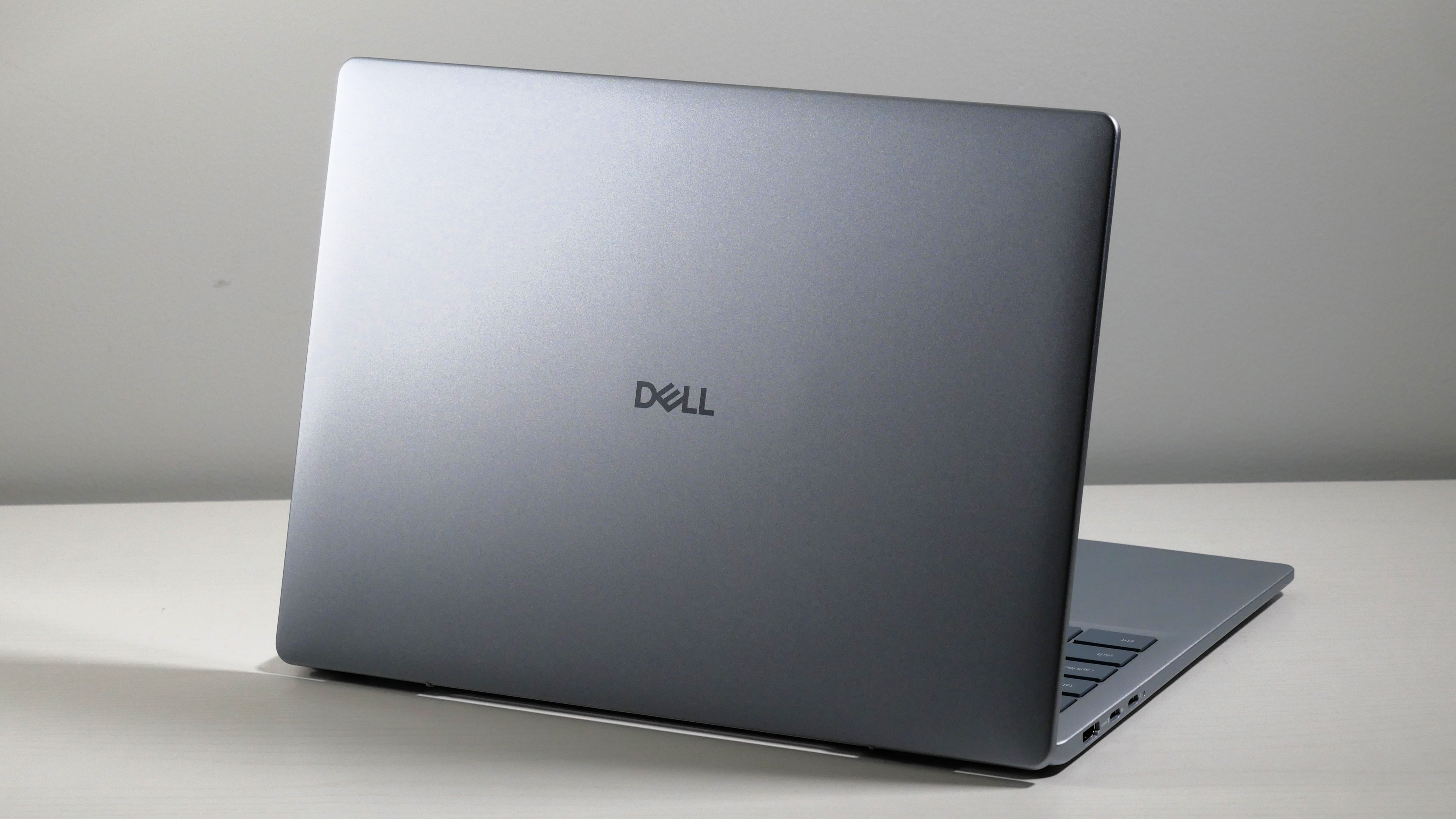 Dell 14 Plus open on a white desk, highlighting the silver lid.