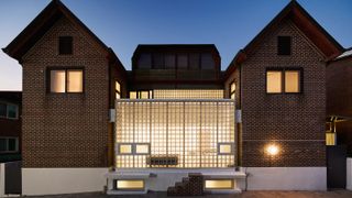 brick and glass house lit from within designed by Studio Heech